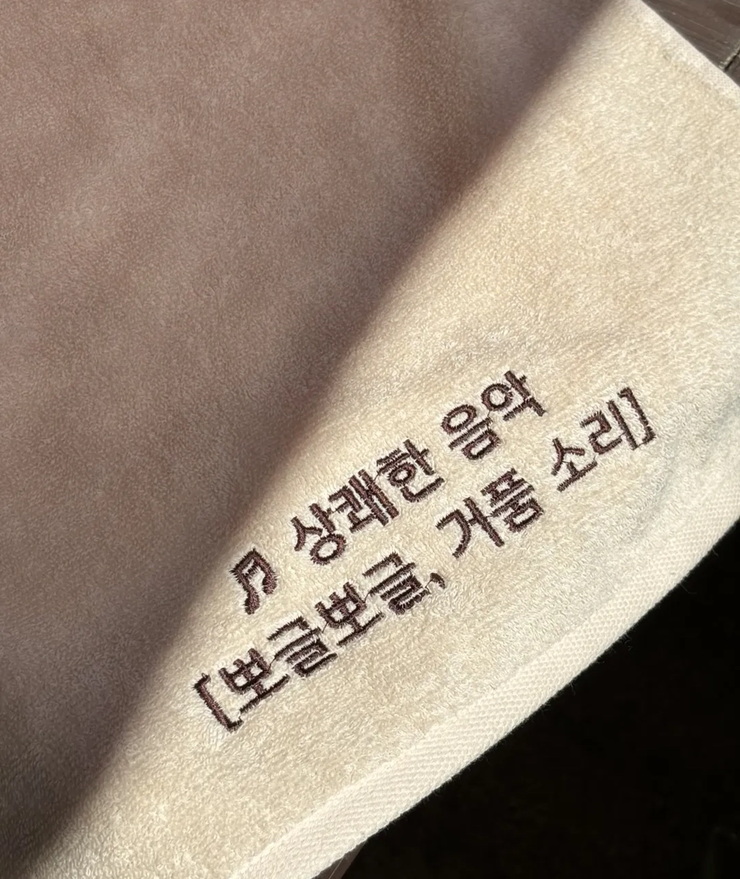 수건에 자수된 배리어프리 자막 표기 "♬ 상쾌한 음악 [뽀글뽀글, 거품 소리]"